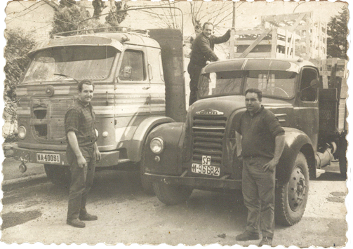 Foto antigua de dos camiones y trabajadores